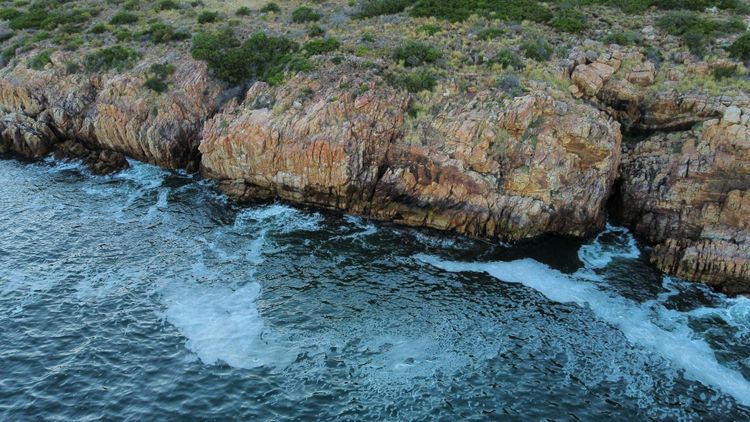 Ocean water moving against a rocky shoreline, showing the steady interaction between waves and stone, representing reality as it is.