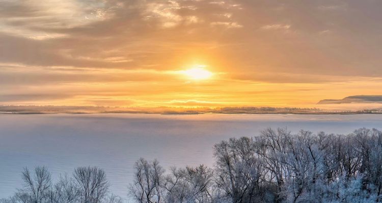 Sunlight breaking through clouds over a cold winter landscape, representing hope without denying difficulty.