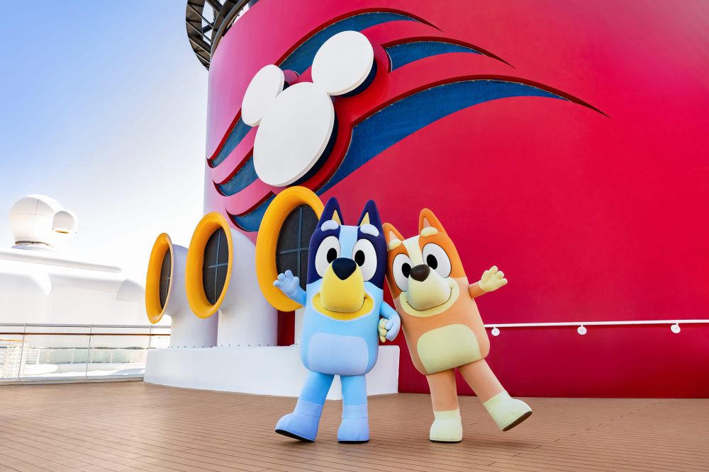 Bluey and Bingo on the deck of a Disney Cruise Line ship, in front of the red funnel