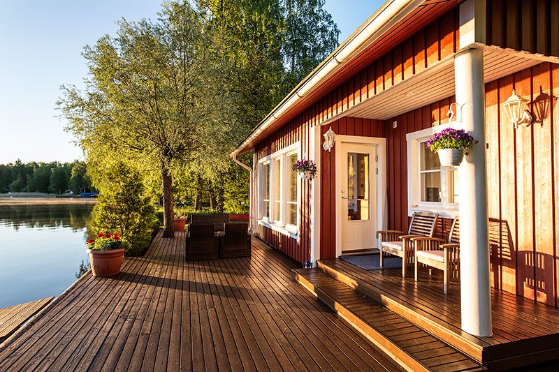 Perinteisen puuhuvila Hiisi Resortin terassi järven rannalla auringon laskussa - Venuu.fi