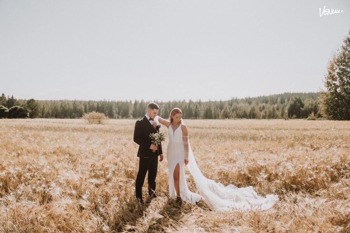 Elisa Niittylä Photographyn taiteenomainen kuva hääparista peltomaiseman ympäröimänä