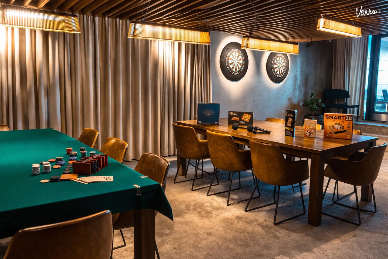 Tunnelmallinen juhlatila, jossa kaksi pöytää, pelejä sekä darts-tauluja