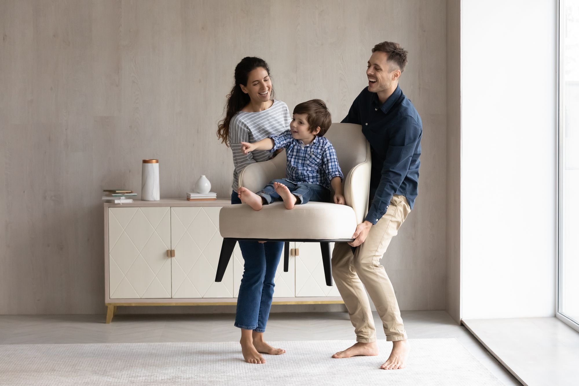 A young mom and dad play with their son while moving furniture into their new home.