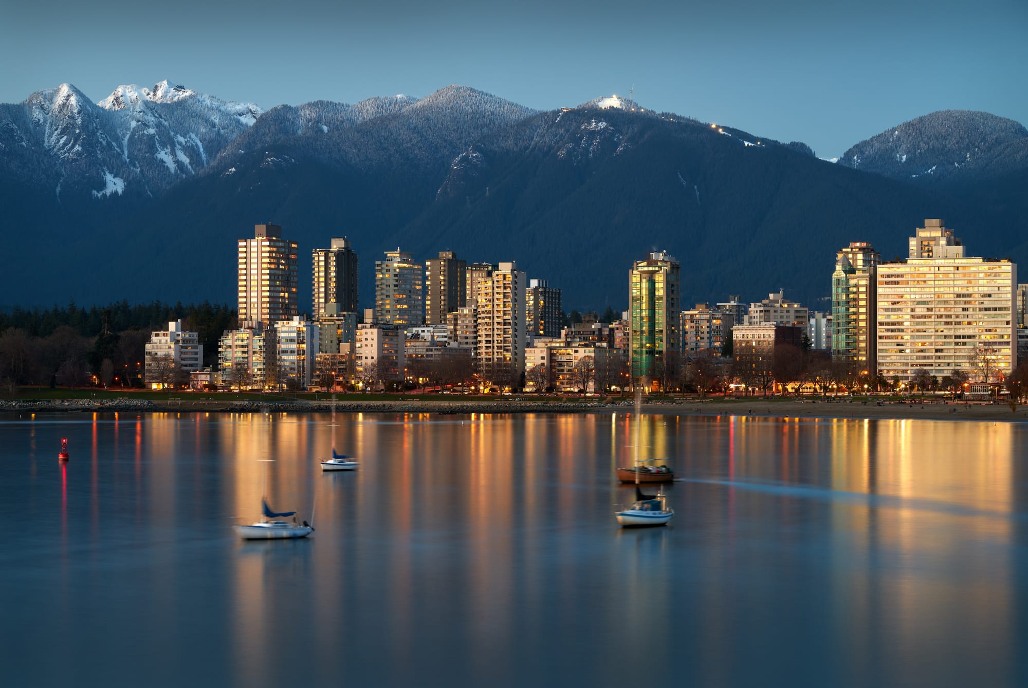 Skyline of Vancouver with mountains in the background and the ocean in the foreground
