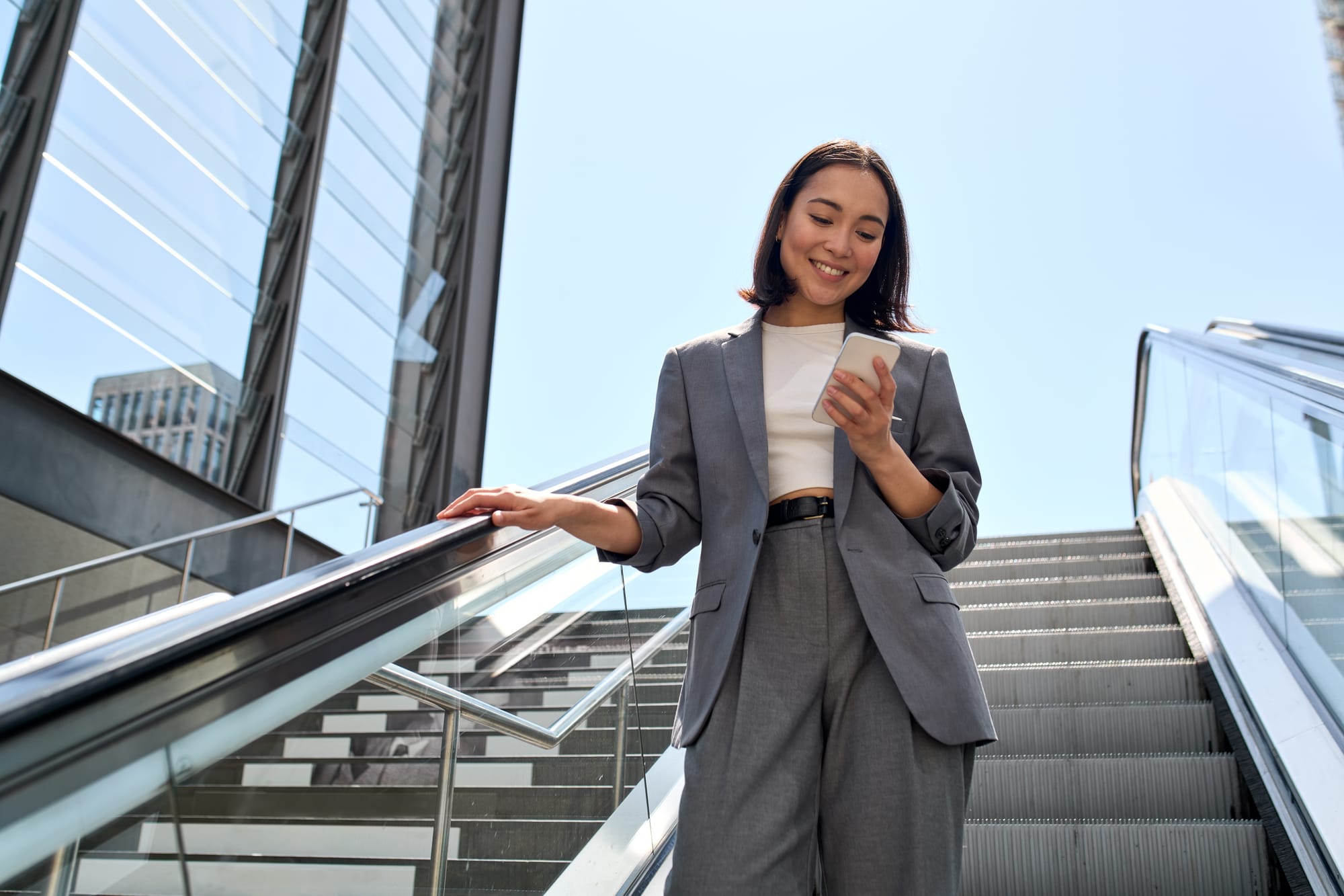 Real Estate Professional looking at her phone screen on an escalator