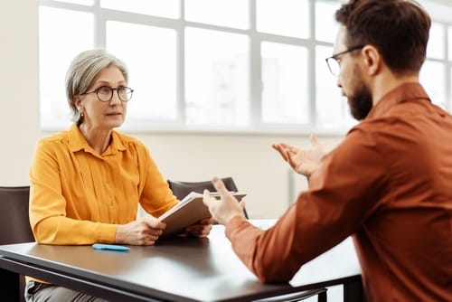 A woman sitting across from an agent during an interview