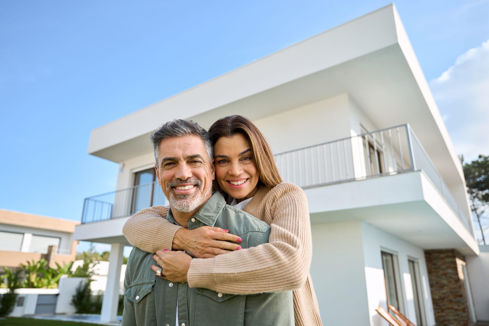 A couple standing in front of a luxury home after working with a luxury real estate agent