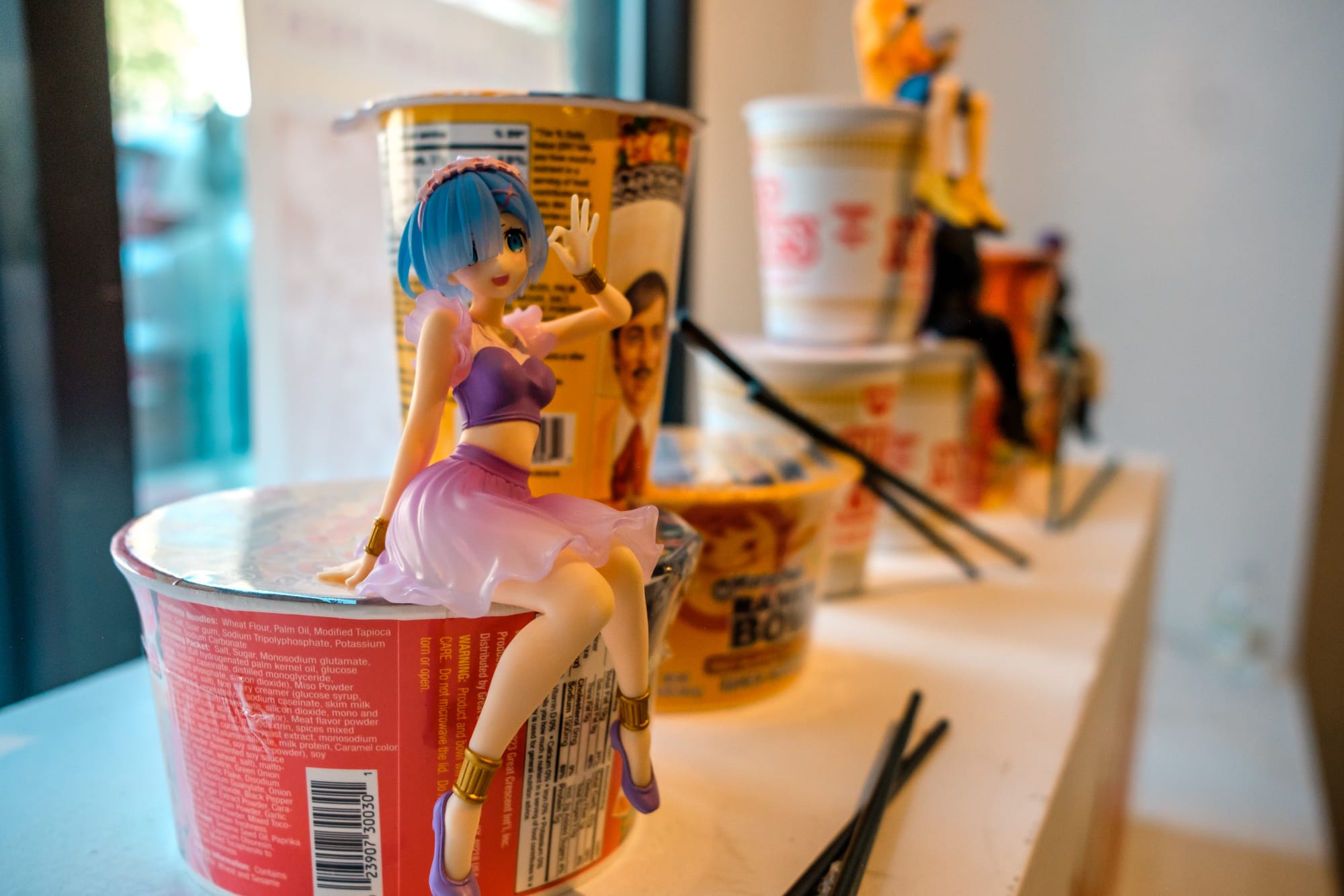 Several bowls of ramen noodles sit on display surrounded by chopsticks and little cartoon figurines sitting on top