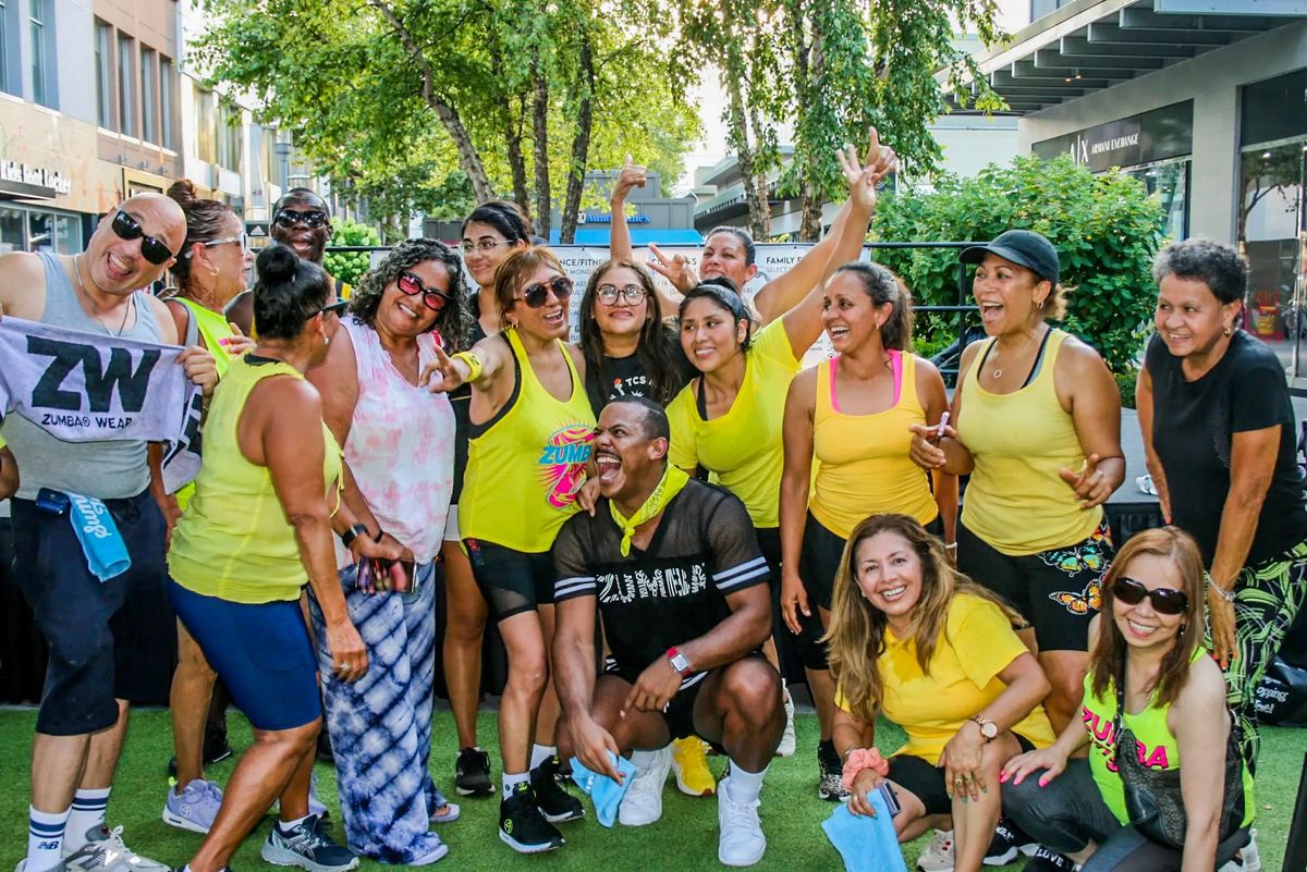 Men and women, dressed in mostly yellow, laugh as they gather together for a group photo