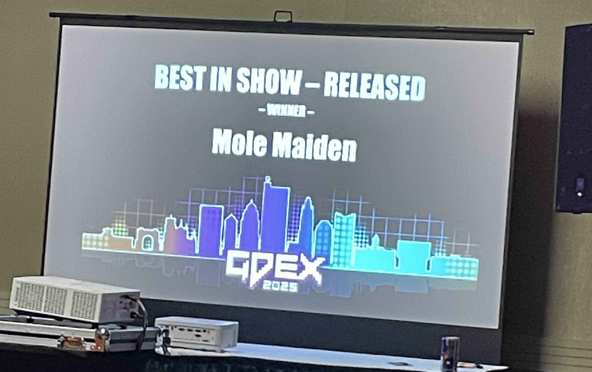 Projector screen announcement of "Mole Maiden" winning "Best in Show - Released" at GDEX 2025