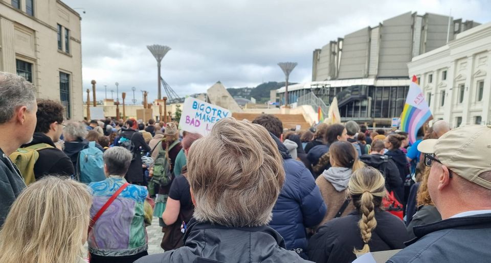 group of protesters, some with signs and trans flags, in Te Ngākau Civic Square