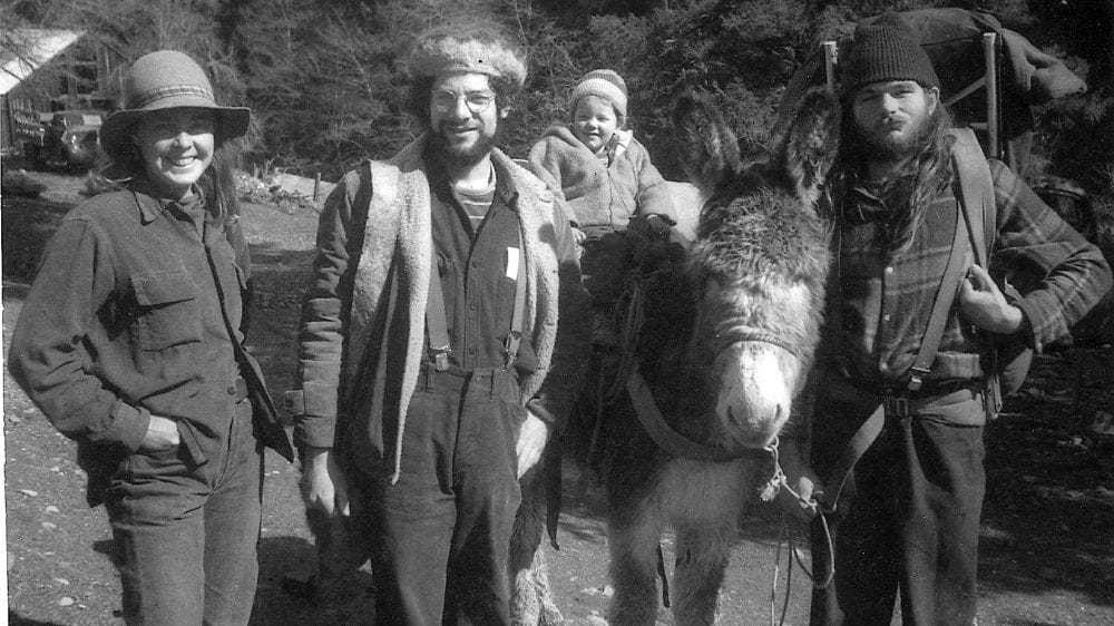 A woman and two men with a child sitting on a donkey.