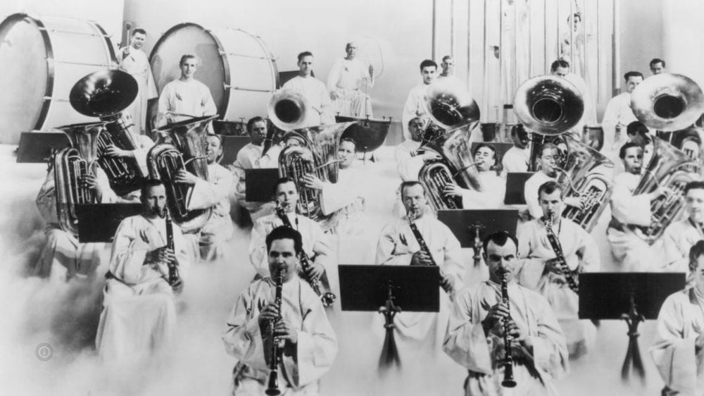 An orchestra full of men in white robes playing large drums, tubas and clarinets surrounded by white clouds.