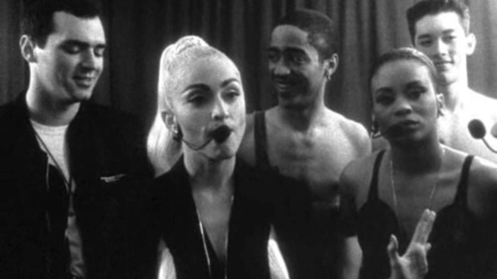 Madonna in black and white with a blonde ponytail stands backstage with her brother, two dancers and a backing singer.