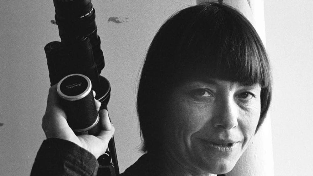 Black and white photograph from the 1970s of Barbara Hammer holding a camera, her hair in a sharp bob.