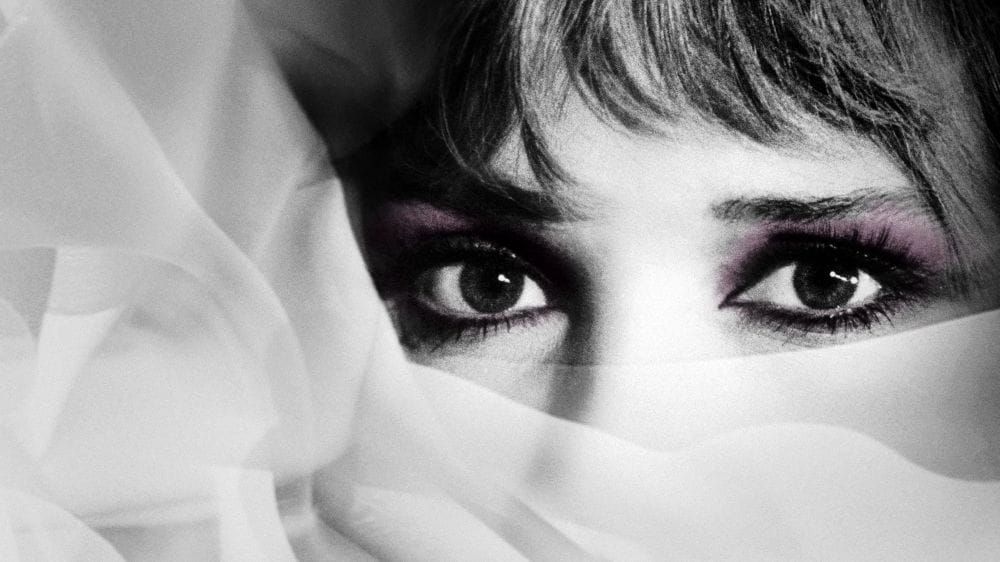 Black and white close-up of a woman's eyes with the rest of her face covered in sheer fabric.