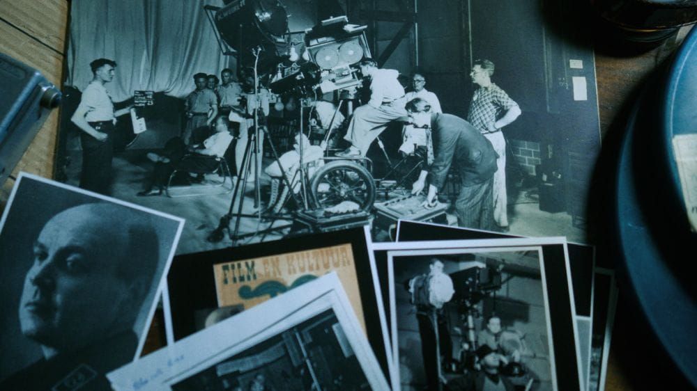A collection of black and white photographs of 1940s film productions displayed across a table.