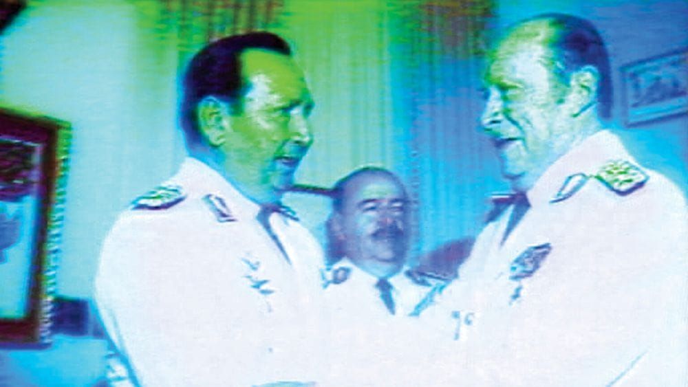 A distorted video still of two Paraguayan leaders in uniform shaking hands.