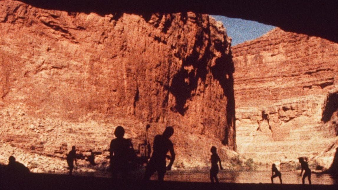 16mm footage of naked naturists in silhouette among the high red rock walls of the grand canyon.