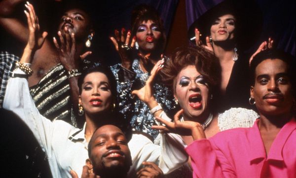 Paris is Burning: A collection of black and latin queer individuals joyfully look at the camera, posing in elaborate costumes and gesticulating with their hands. 