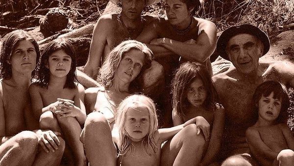 In sepia colours, women men and children sit around in nature.