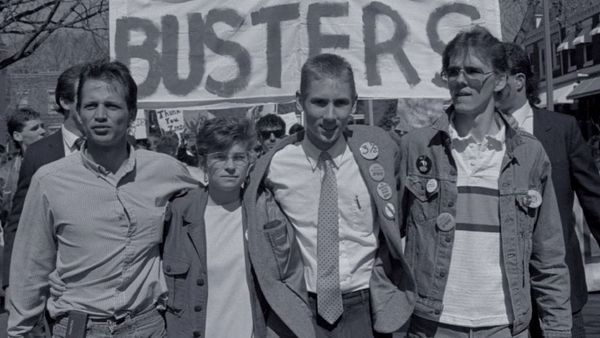 Black and white photo of four young college activists from 1988 arm-in-arm.