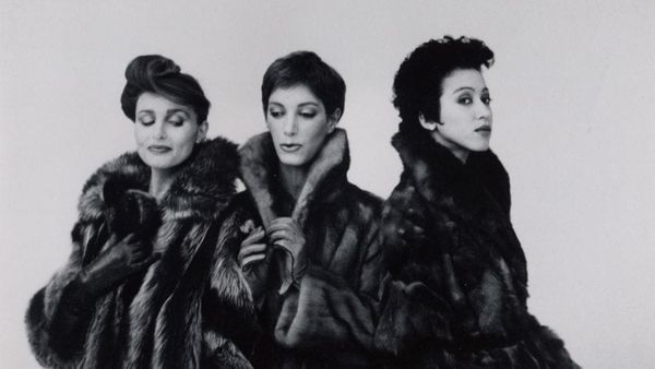 Three dark-haired women pose in fur coats.