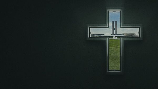 A cross is carved out of a stone wall and through it is Brazil's parliamentary building.