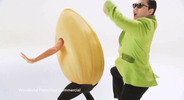 South Korean pop star Psy dressed in a pistachio-green suit and sunglasses dances with a life-size pistachio nut (yes really)