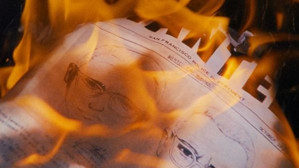 A wanted poster with two facial drawings on it goes up in flames.