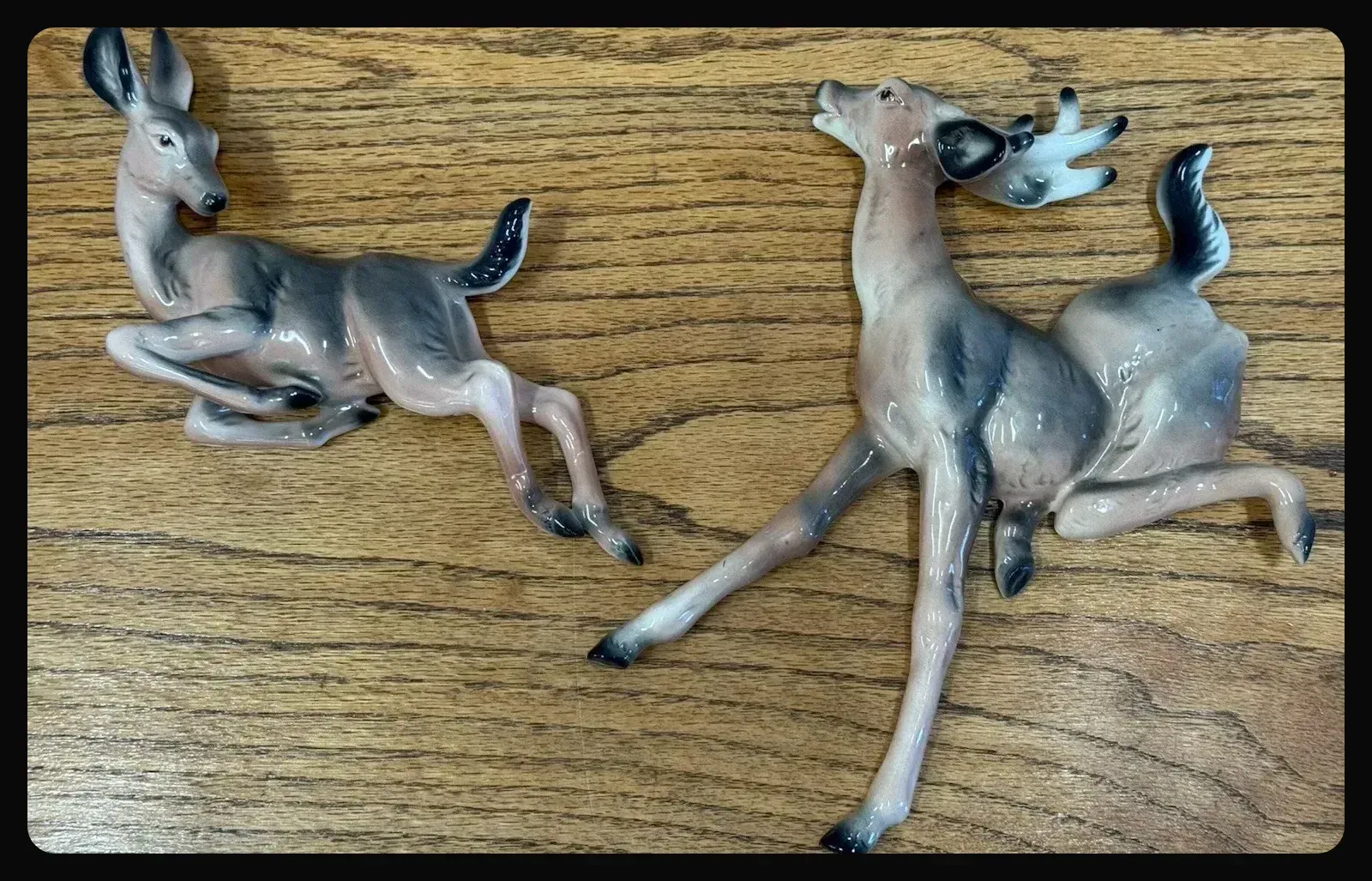 A ceramic decoration of a black, white and brown stag chasing after a doe.