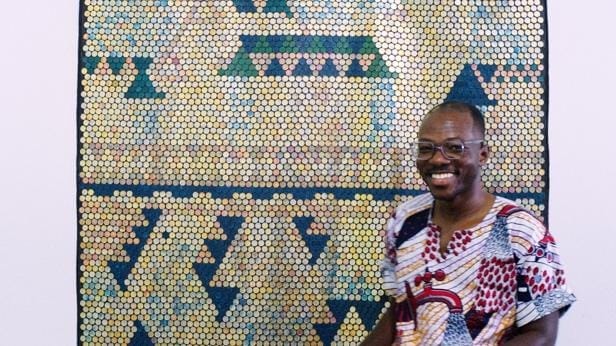 A person smiling in front of a mosaic
AI-generated content may be incorrect.