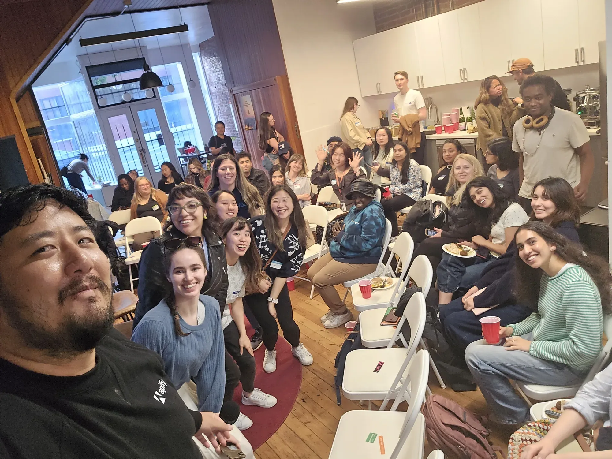 A packed room of attendees smiling at the camera during an Apify community event in San Francisco