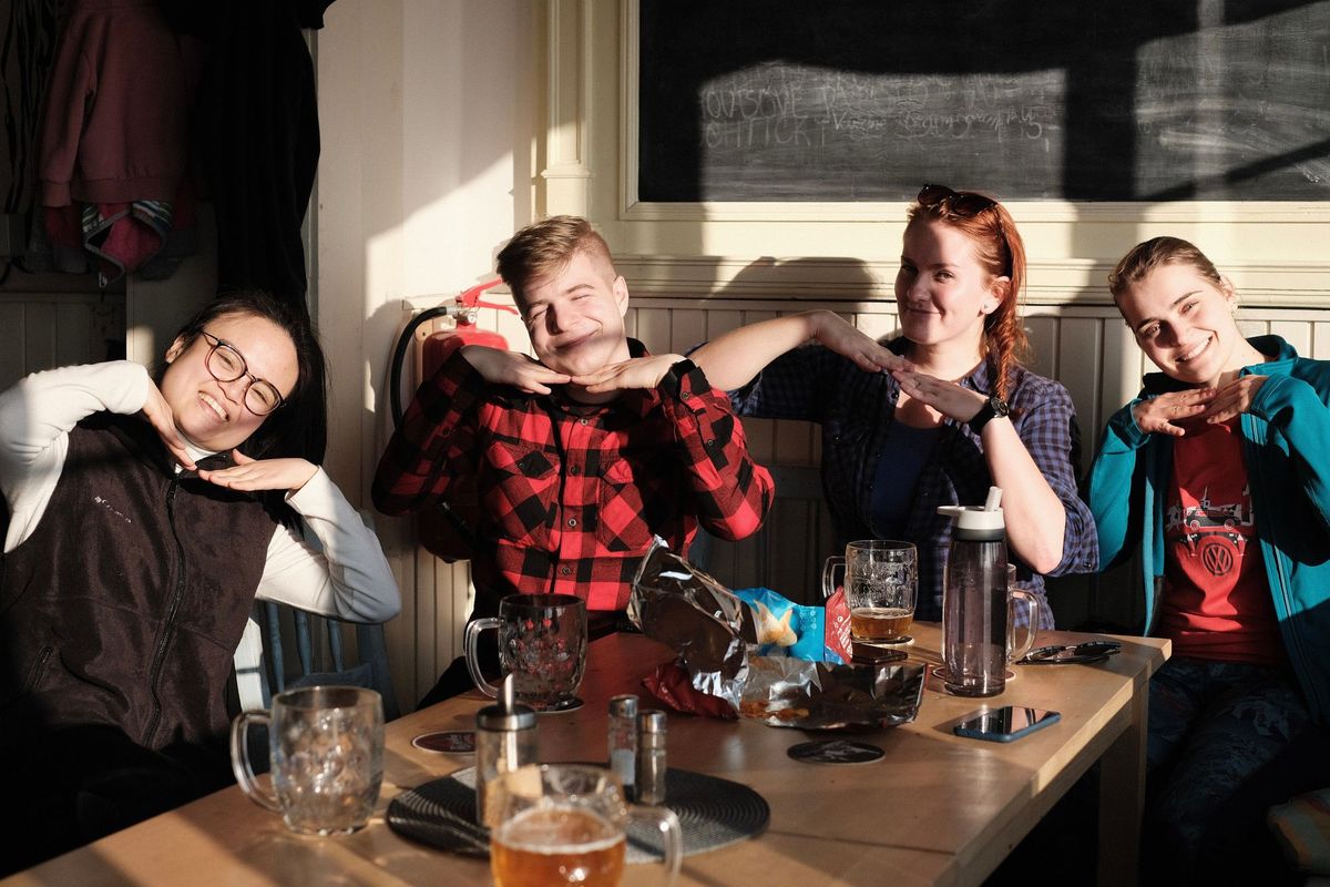 Four Apifiers sitting around a table, smiling and having a beer together.