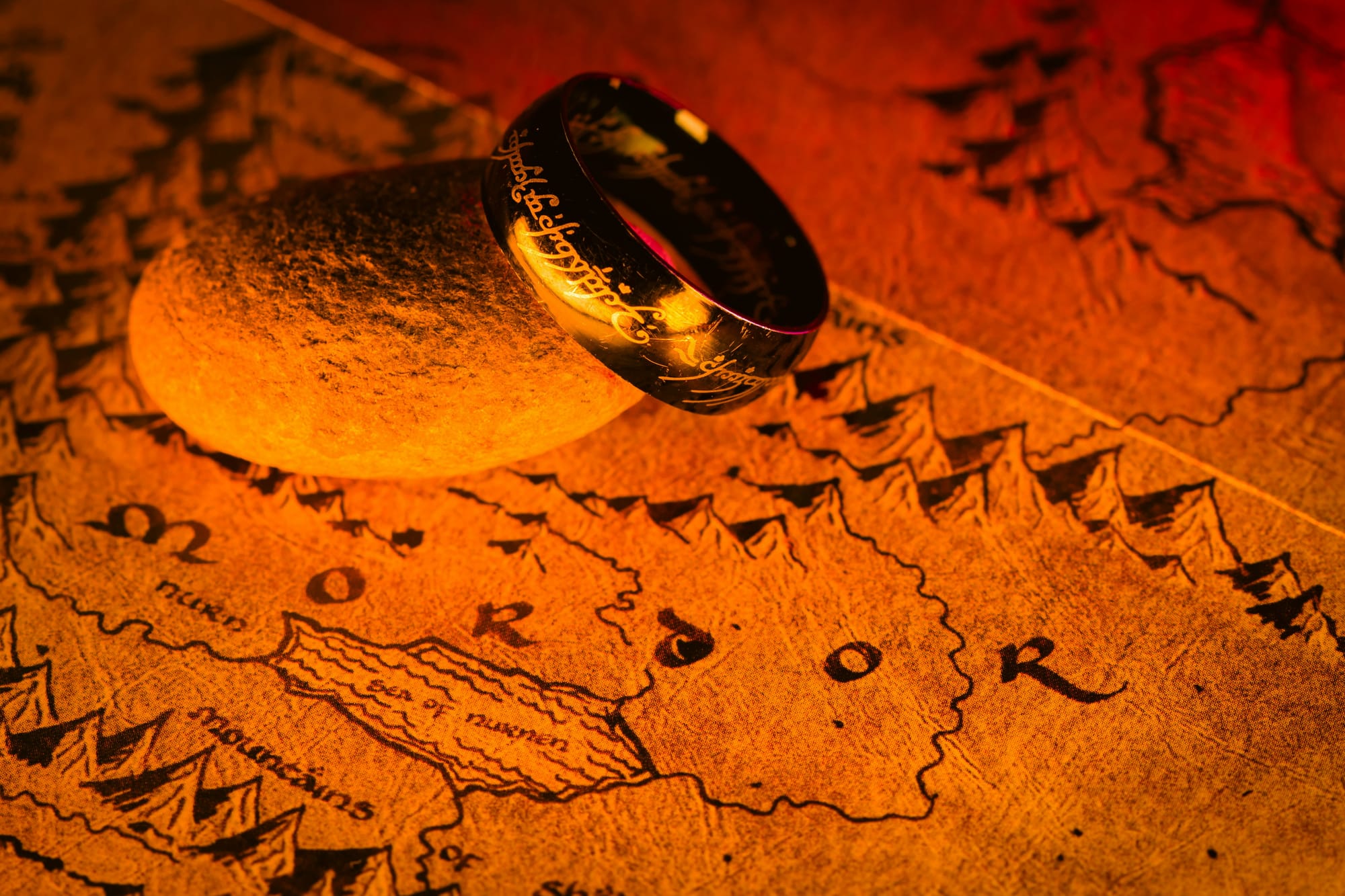 A photo of a replica of The One Ring resting against a map of Middle-earth.