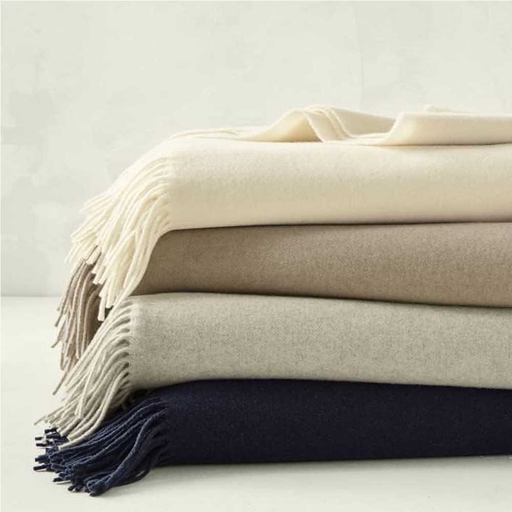 Elegant beige cashmere blanket folded neatly on a sofa — a luxurious and comforting gift that adds warmth and style to Grandpa’s space