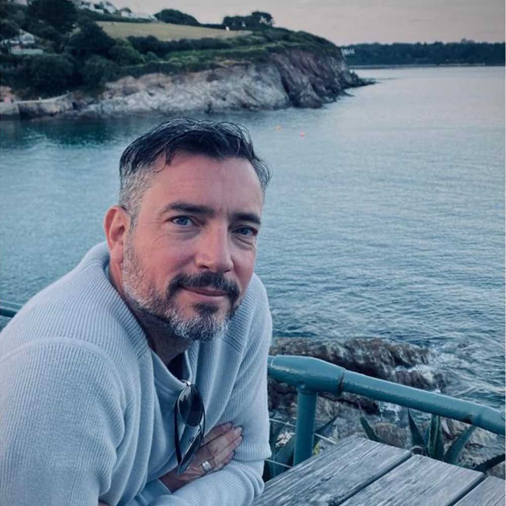James, the real dad behind The Gifting Dad – smiling at a seaside table
