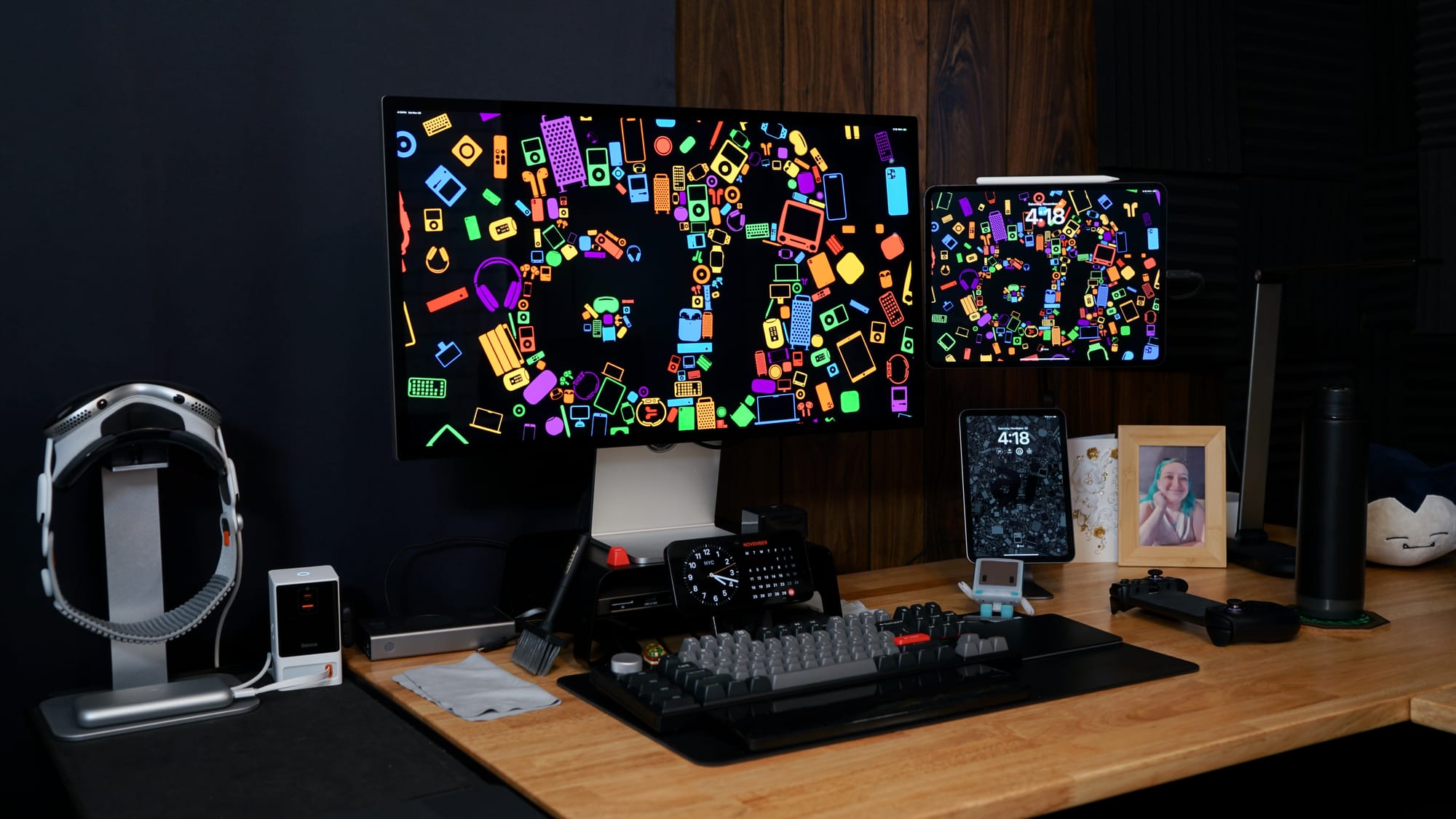 iPad Pro connected to Studio Display, iPad mini below, Apple Vision Pro in a stand beside, on a wood desk with a mechanical keyboard.