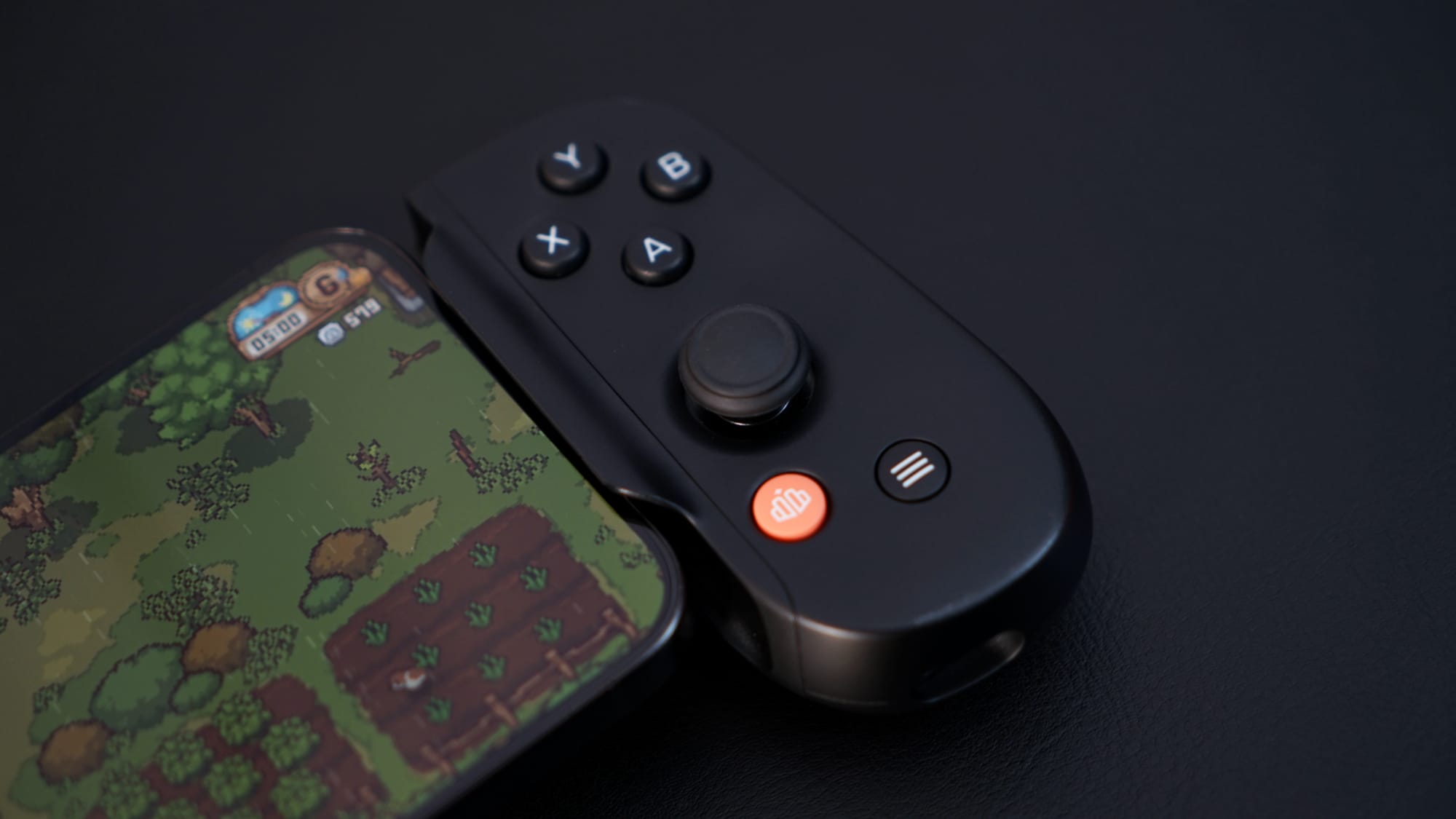 An iPhone with a farming game on screen, the device is in a controller grip