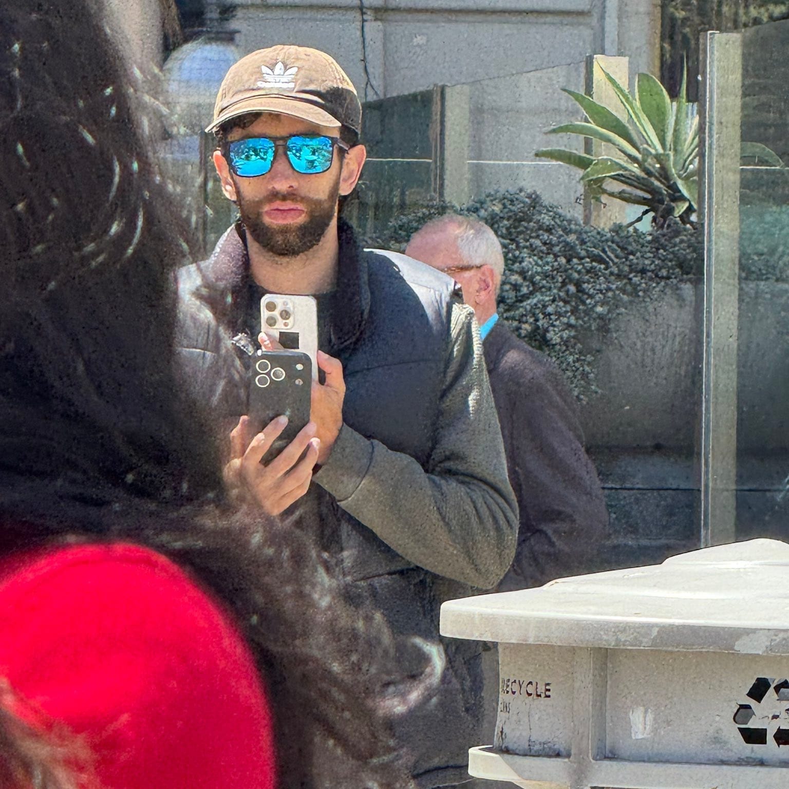 A person with reflective sunglasses holding two iPhones, one of which appears to be the iPhone 17 Pro