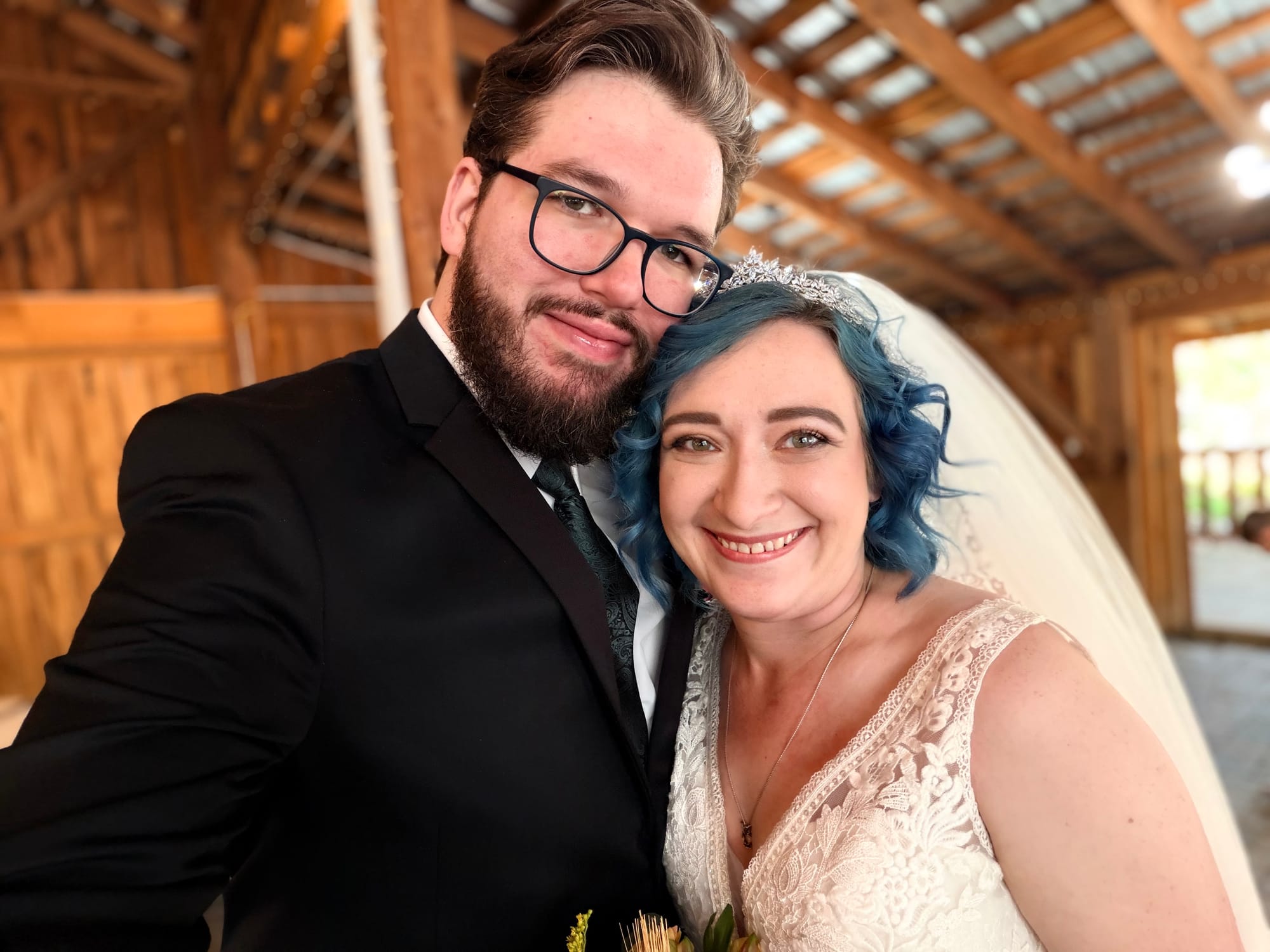 A bride and groom dressed in wedding attire, the bride Natalie with blue hair and Wesley with his beard and glasses