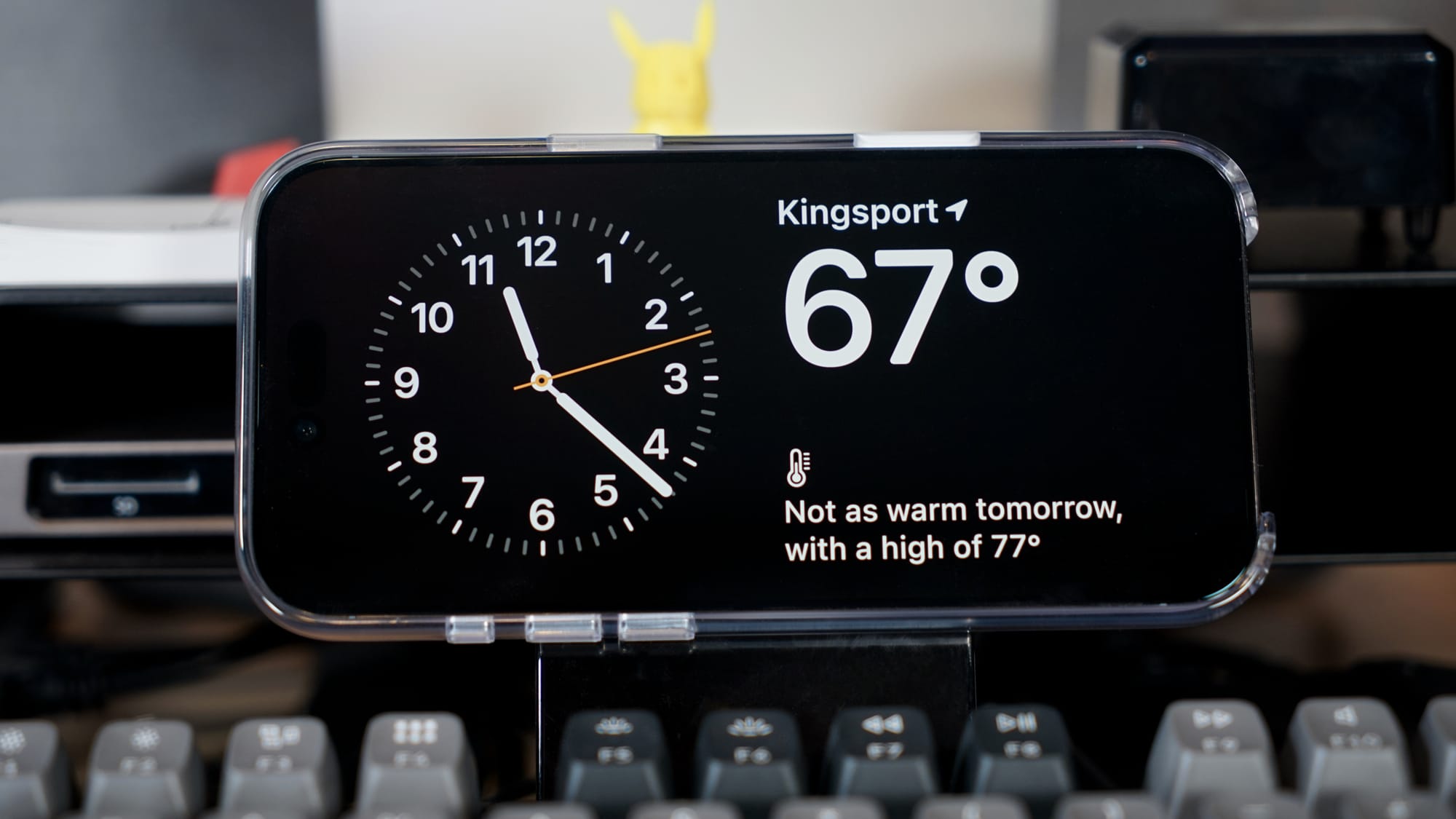 An iPhone Air in a MagSafe Mount above a mechanical keyboard, it shows the time and weather