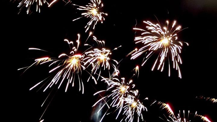 Fireworks bursting in the night sky making yellow-white blooms