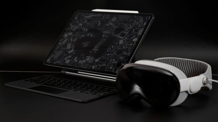 An iPad Pro in a Magic Keyboard with an AppleInsider wallpaper next to an Apple Vision Pro on a dark surface