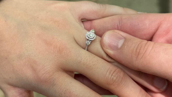 A photo of an engagement ring placed on a finger