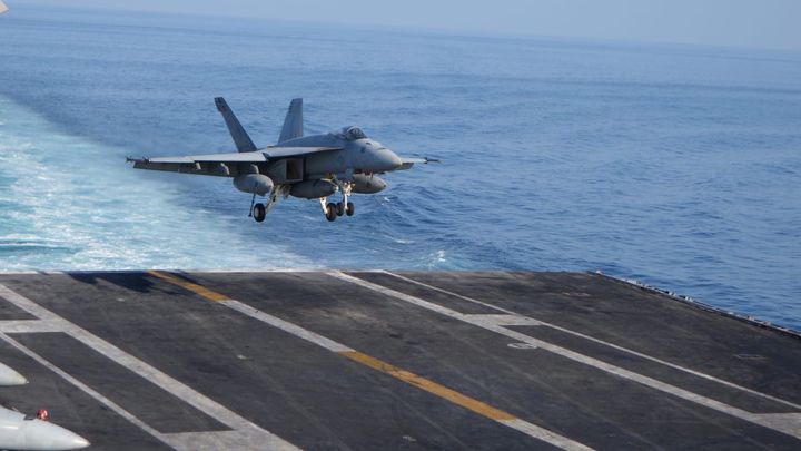 A fighter jet landing on an aircraft carrier