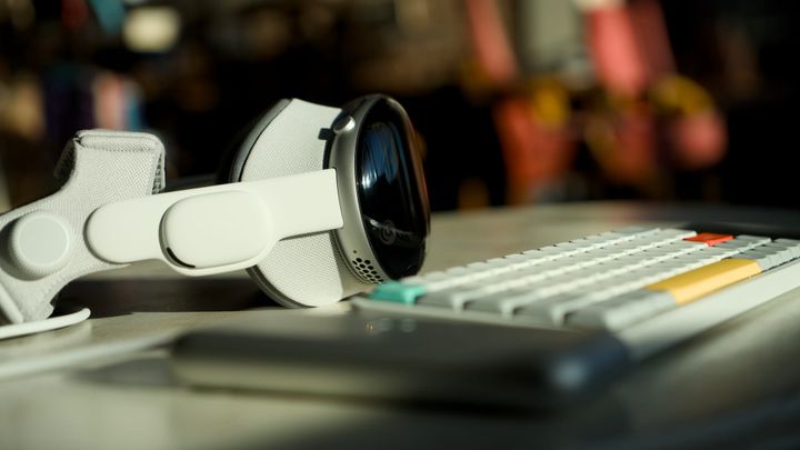 Apple Vision Pro on a table beside a compact mechanical keyboard