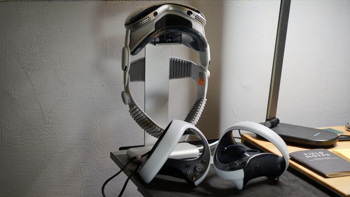 Apple Vision Pro on a stand behind two PlayStation VR2 controllers