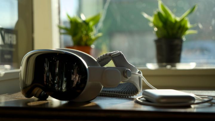 Apple Vision Pro on a table in a cafe backlit by the sun, two plants in a window on a sill