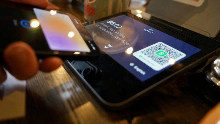 An iPhone showing Apple Pay with Apple Card at a payment kiosk in a coffee shop